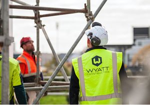 Workmen on construction site in high visibility vest with Wyatt Construction logo